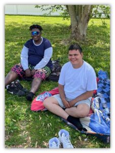 Two young men sit outside near a tree