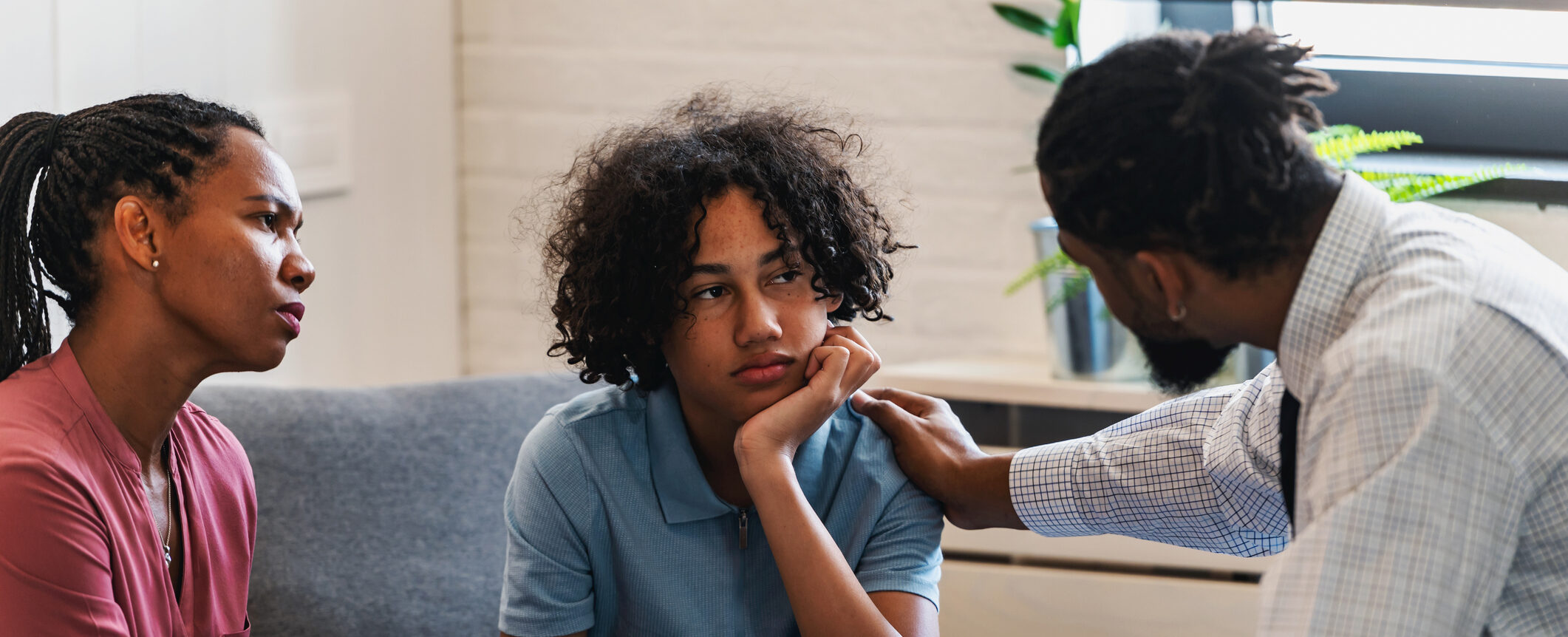 Parent sits with child and a mental health clinician, having a conversation 